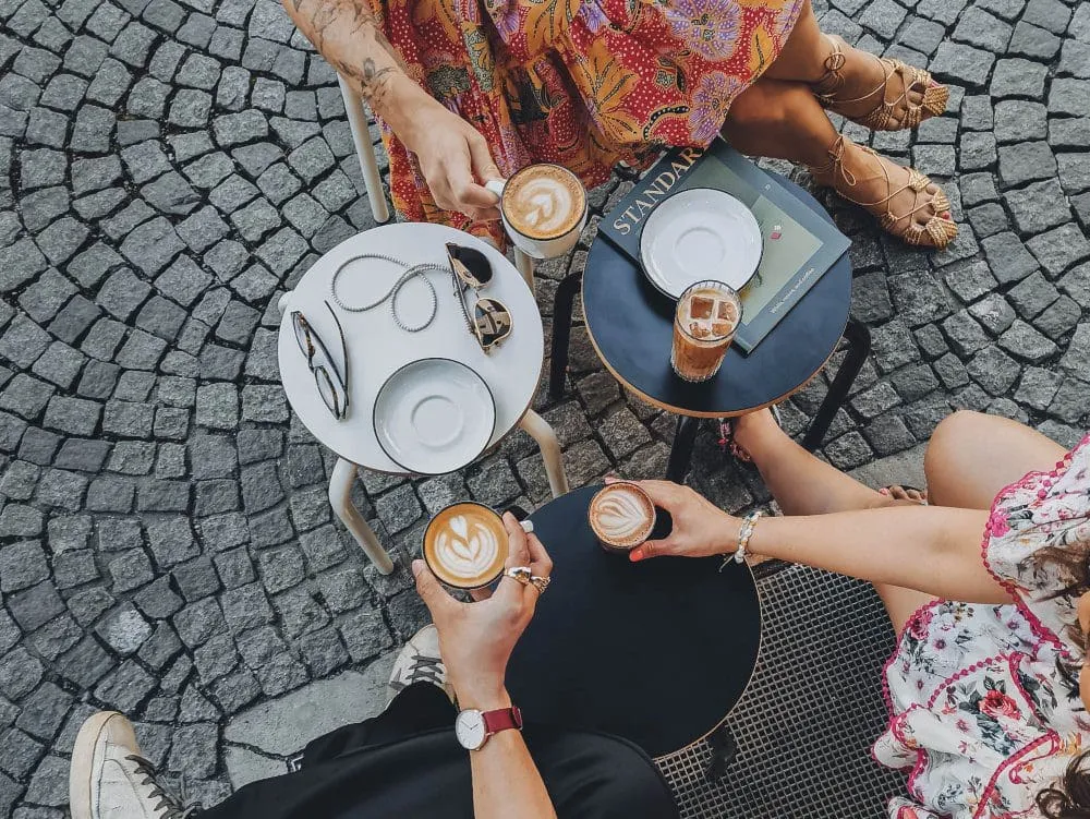 friends holding coffee mugs around table