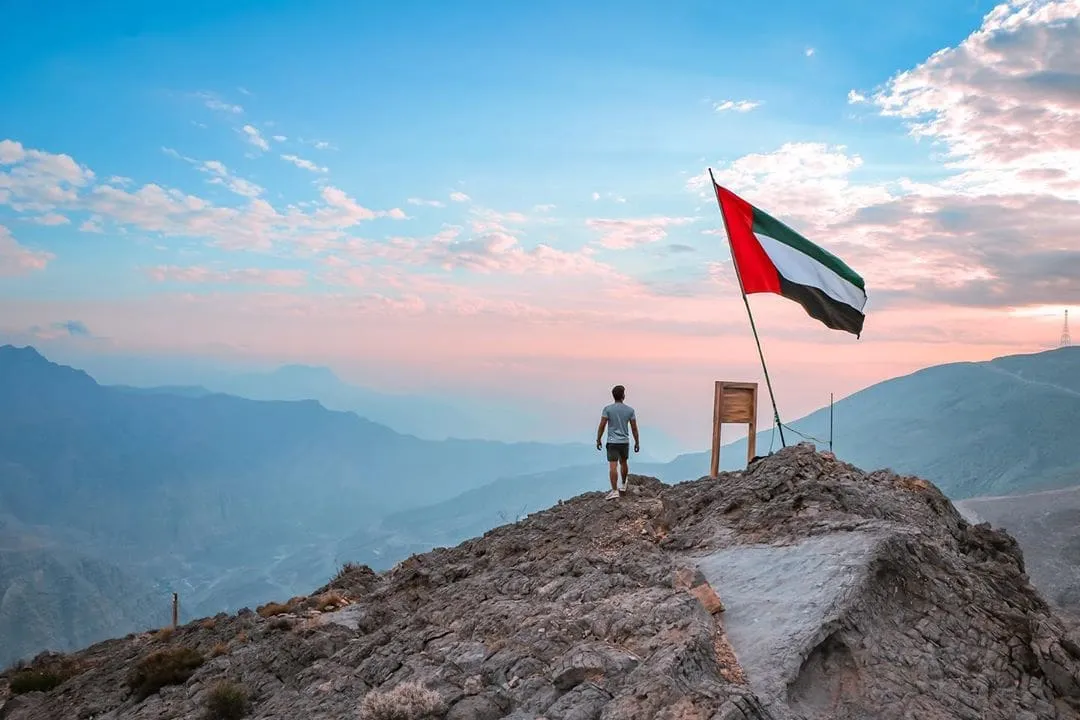 man on mountain with flag