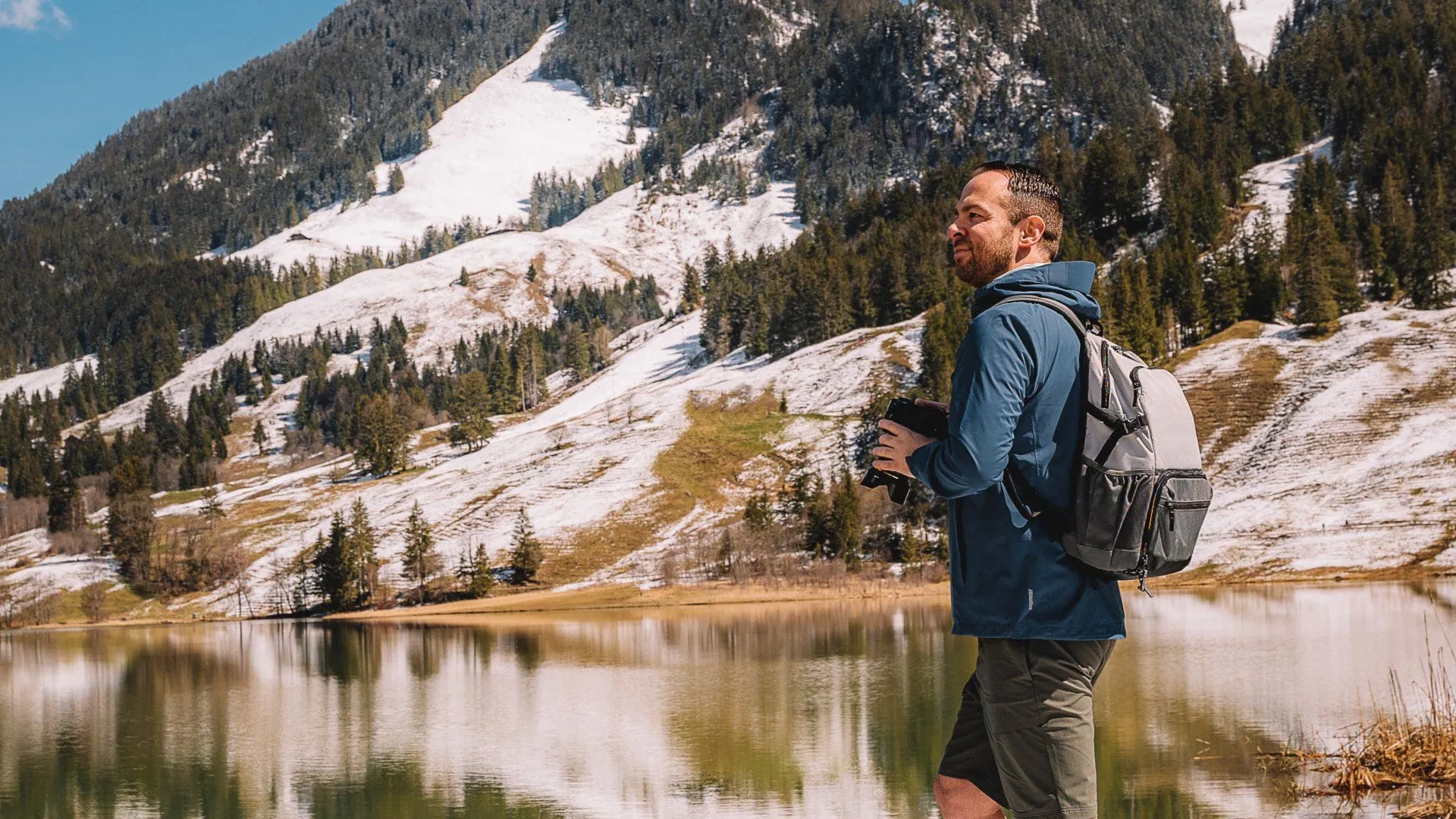 Hiker standing in front of a lake and mountain landscape