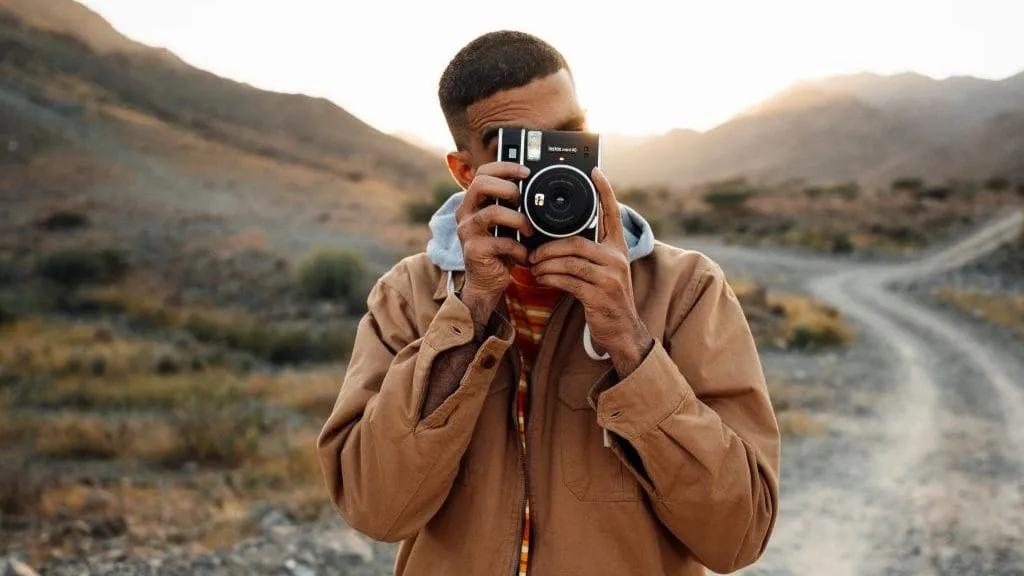 man holding a camera up to his face in a desert landscape capturing content
