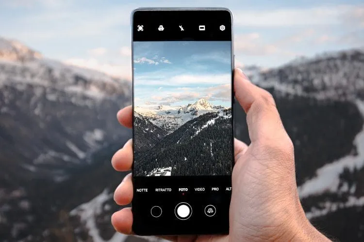 man pointing phone to mountainous scenery