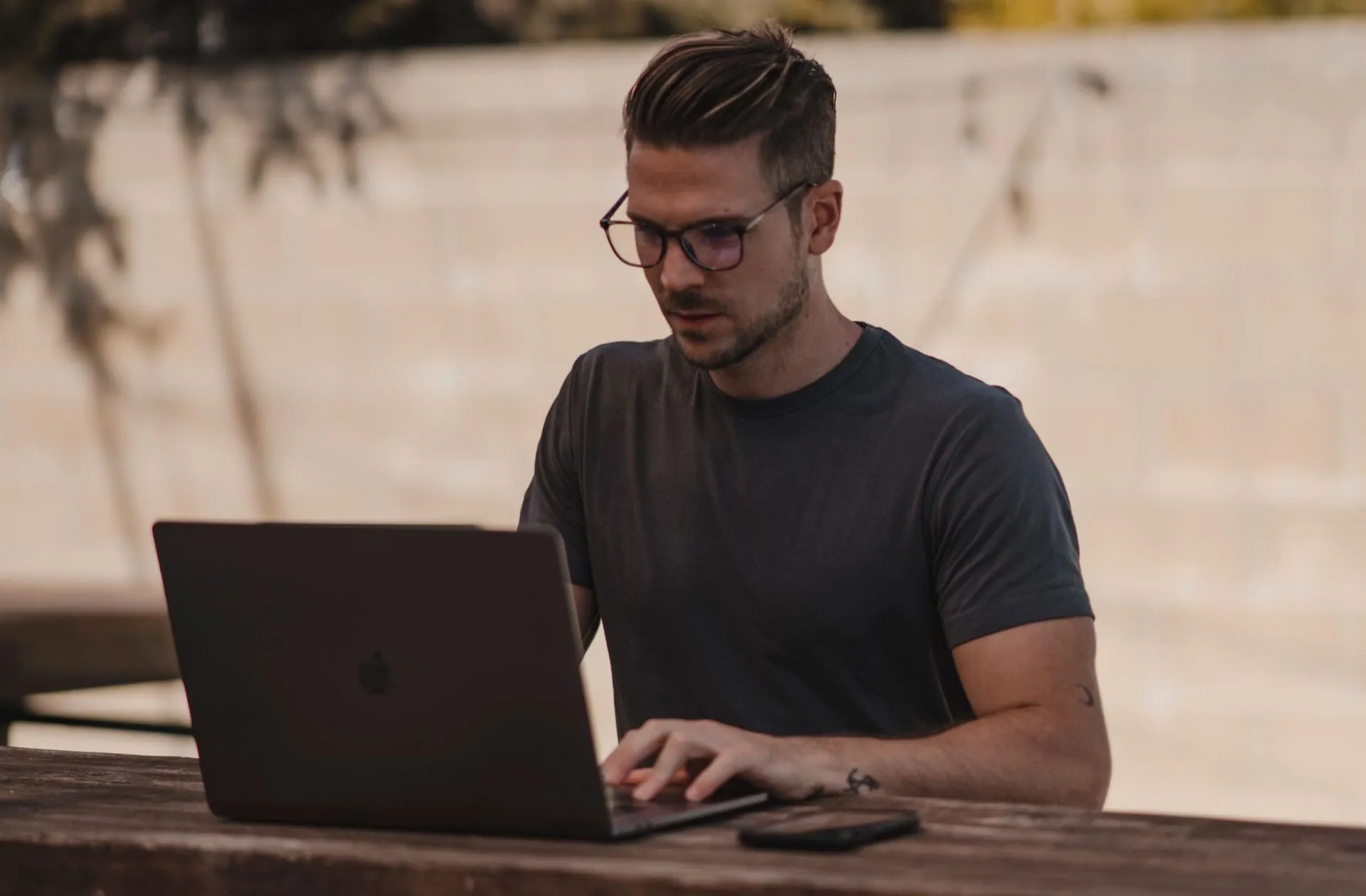man with glasses on laptop outside