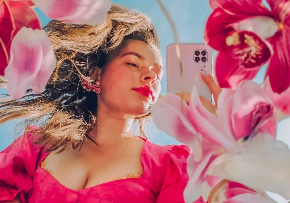 woman on phone in pink dress surrounded by pink flowers
