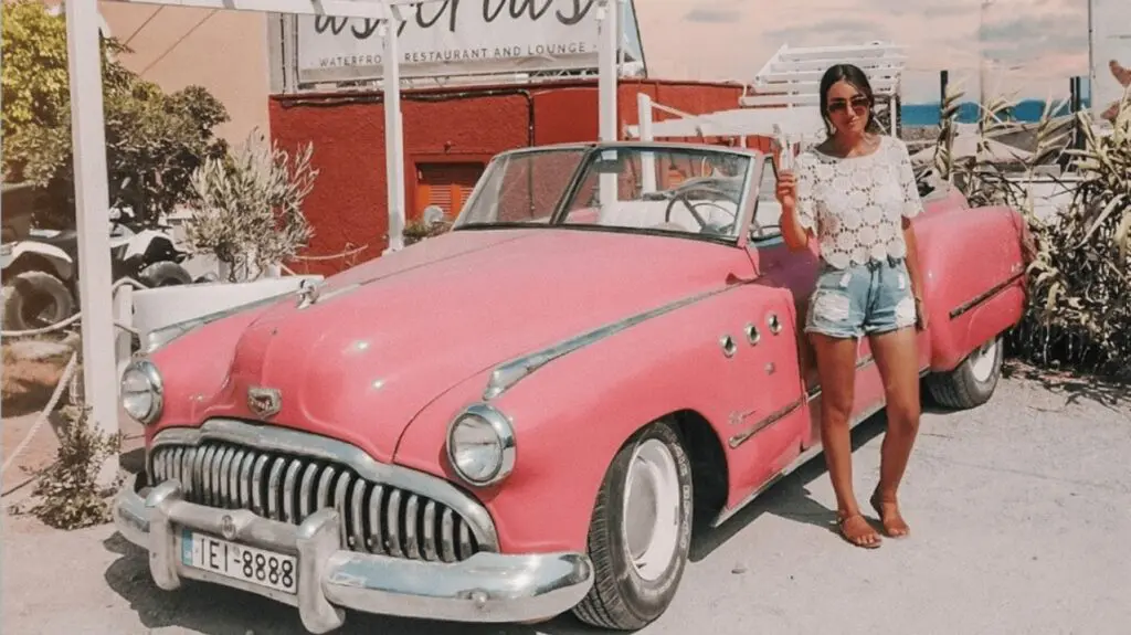 woman next to pink car
