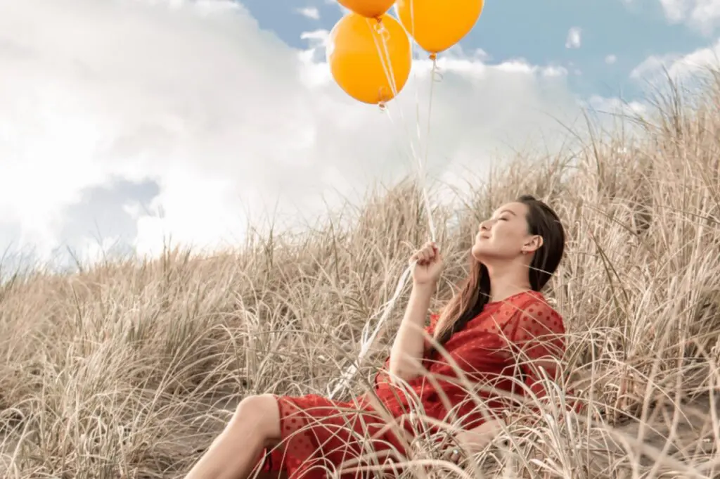 woman sitting in field with balloons
