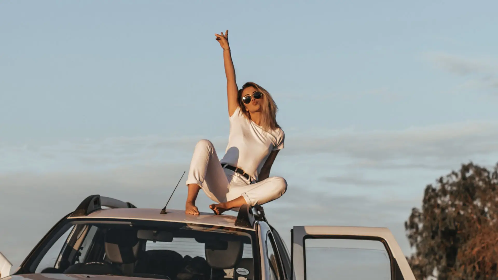woman on top of car with peace signs