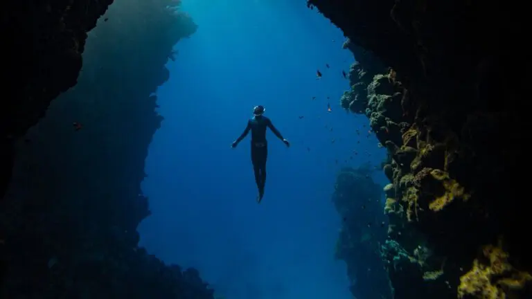 person underwater in between two ocean cliffs