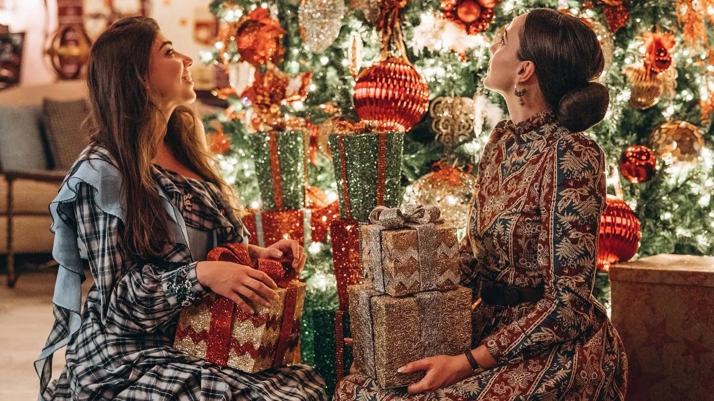 two women sitting in front of christmas tree