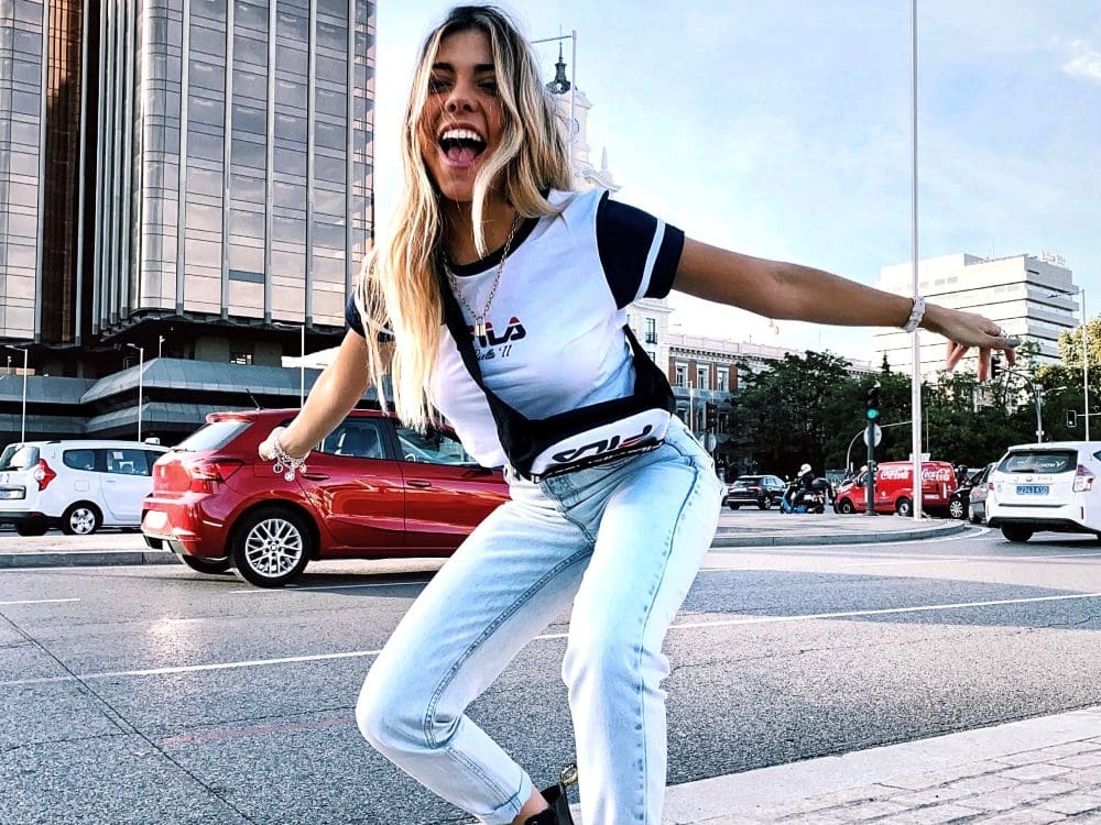 woman in fila t shirt and light blue jeans dancing by road
