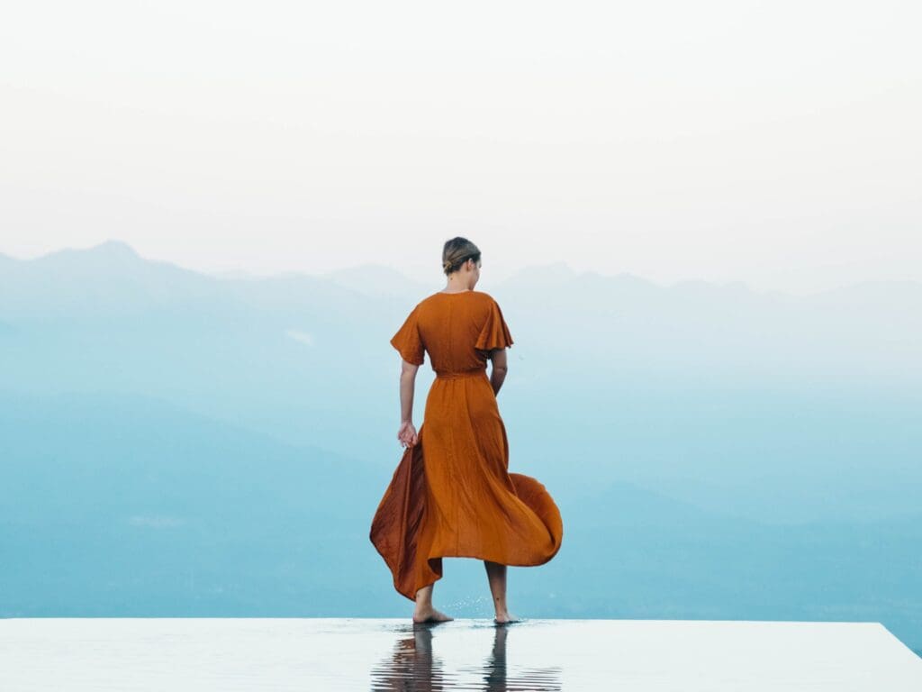 woman in orange dress standing on infinity pool