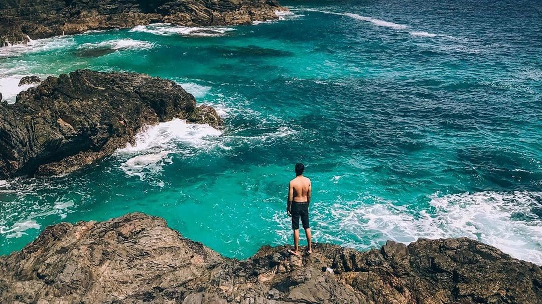 man on cliff edge by sea