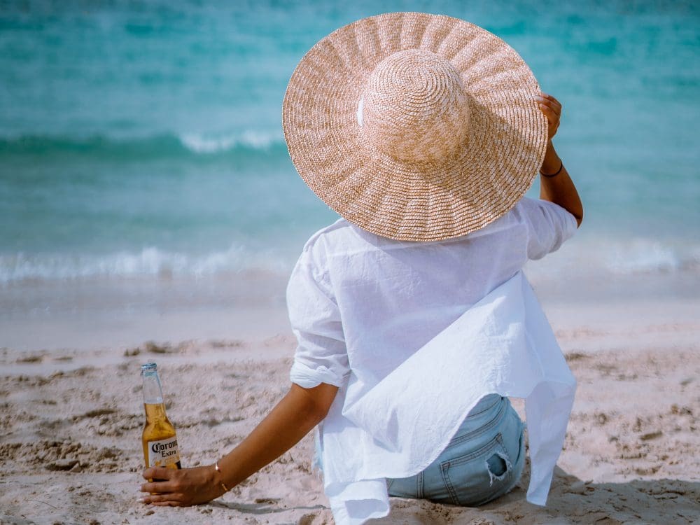 woman on beach with straw hat and beer beeoncloud9 @vistadelverdedxb