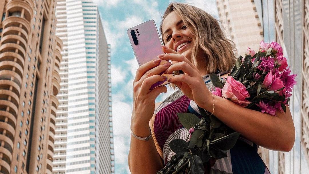 woman on phone with flowers in hand magdajano - Huawei