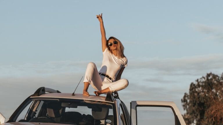 woman on top of car with peace signs