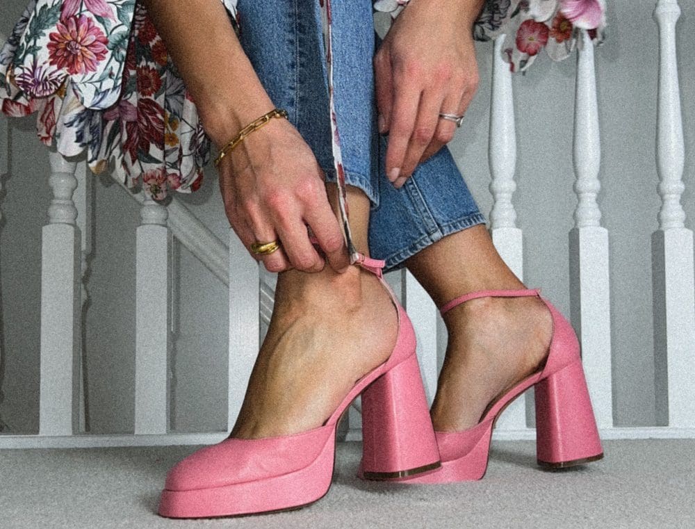 woman buckling up pink high heels