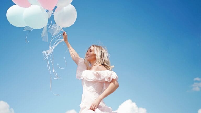 woman holding balloons to blue sky