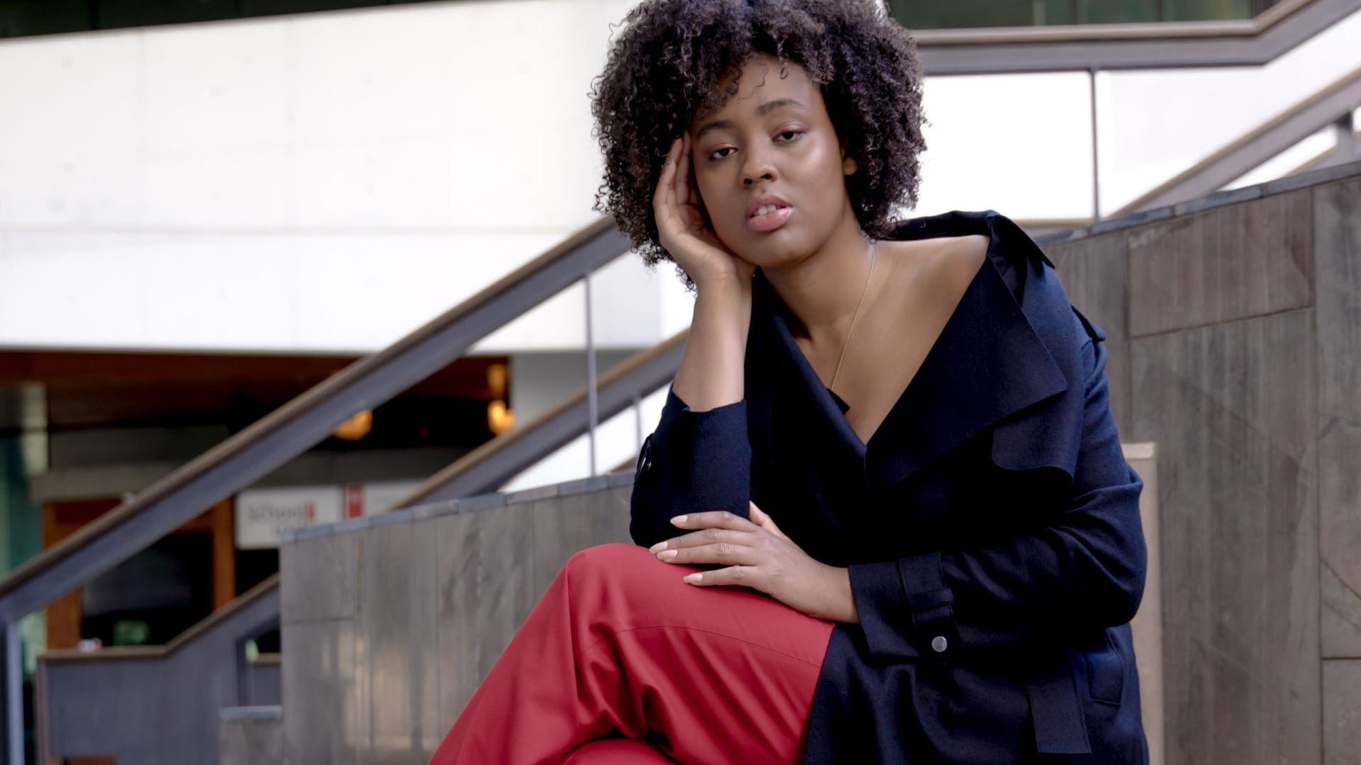 woman sitting with legs crossed in blue coat and red trousers _thefashionheist @sabastyle