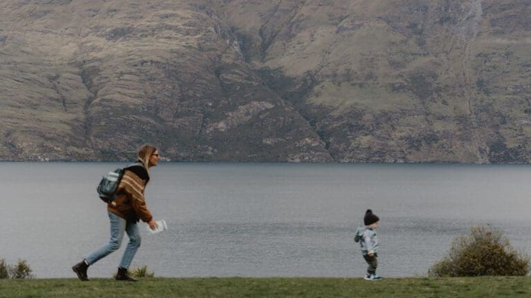 woman chasing her child next to lake