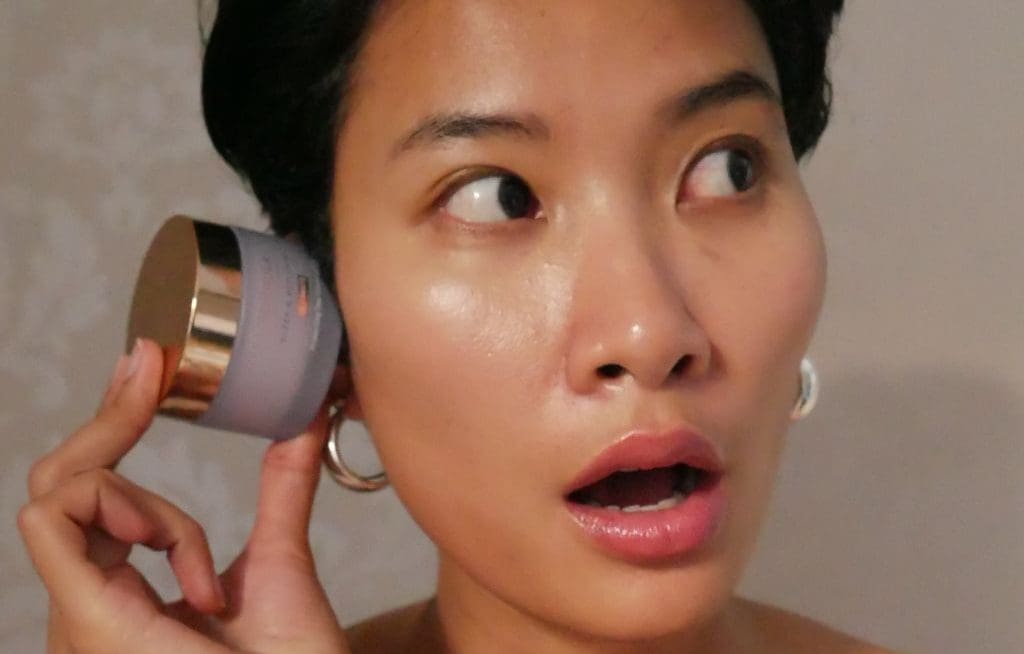 woman holding makeup pot to ear