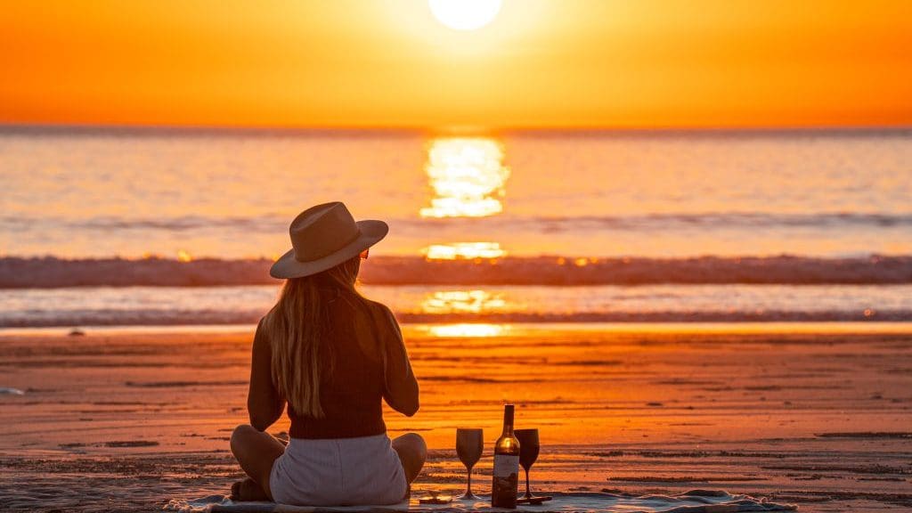 woman on beach having sunset picnic
