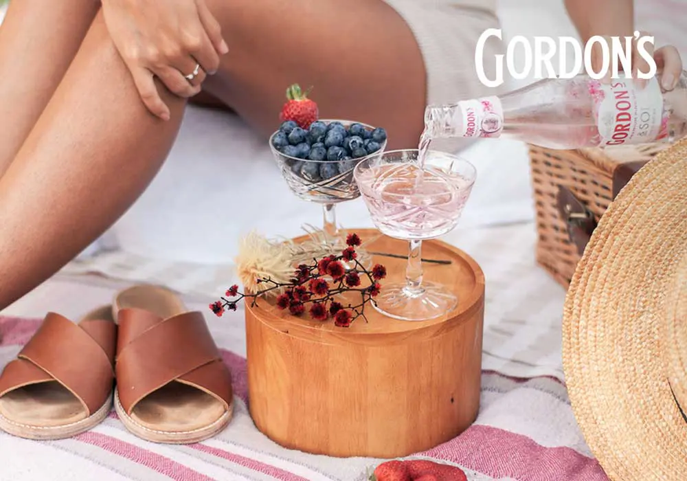 gordons gin being poured into a glass on a picnic blanket