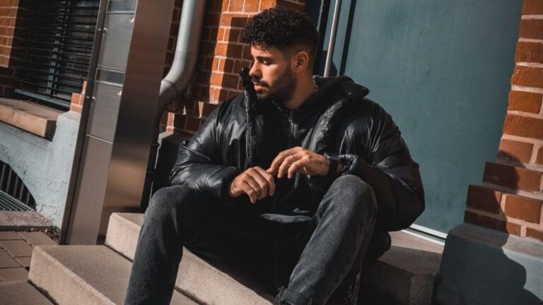 man sitting on door step in black puffer jacket