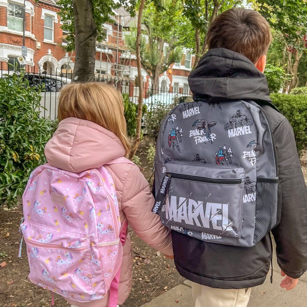 brother and sister walking through park wearing backpacks