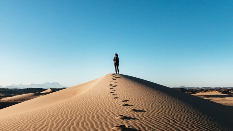 woman standing at top of sand dune