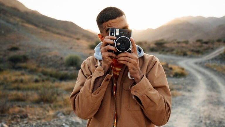 man holding camera up to his face in desert landscape